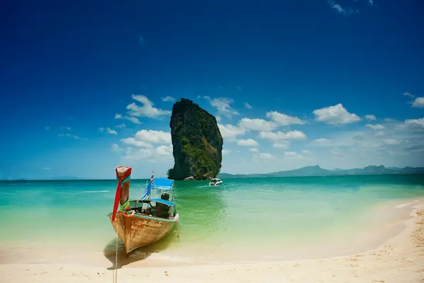 Long-tail boat on turquoise water with limestone karst at Railay Beach, Thailand